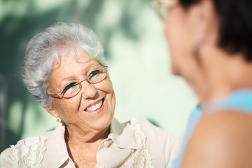 Old friends, two happy senior women talking in park