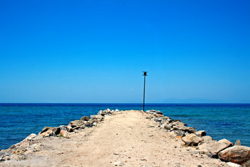 Looking down empty pier towards the sea