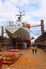 A large cargo ship is being renovated in shipyard.