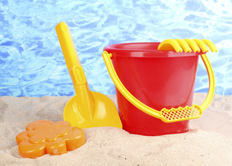 Children's beach toys on sand on water background