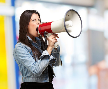 portrait of young woman screaming with megaphone indoor