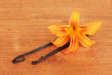Vanilla pods with flower on wooden background