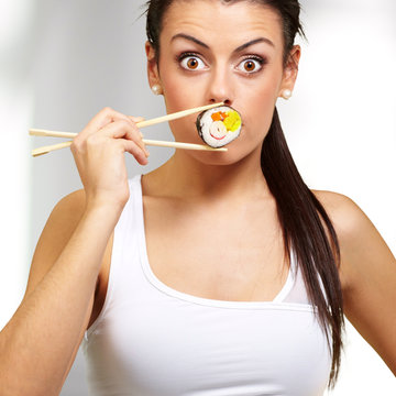 young woman covering her mouth with a sushi piece, indoor