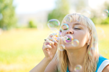 .Woman blowing bubbles in park