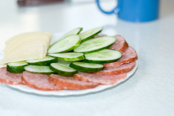 Cut cheese, sausage and cucumber in a plate