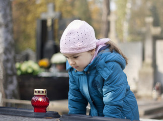 Girl mourning at the grave on cemetery in Warsaw