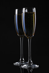 two glasses of champagne on black background