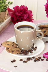 cup of coffee, cookies and flowers on table in cafe