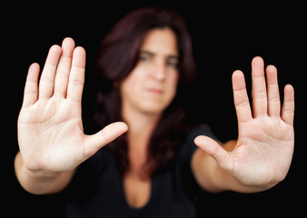 Woman with her two hands signaling to stop on a black background