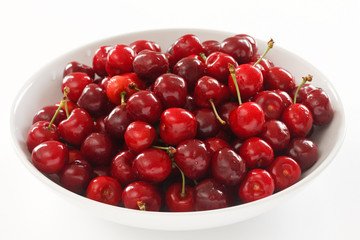 Ripe red cherries in a large white ceramic bowl