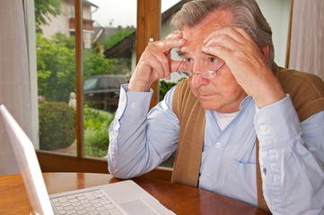 Senior sitzt genervt vor dem Laptop