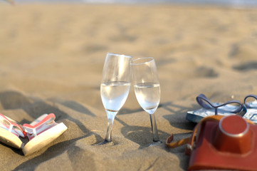 Two glasses, slippers and old camera in the sand