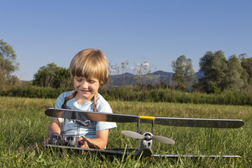 Cute young boy and his RC plane, sitting on grass