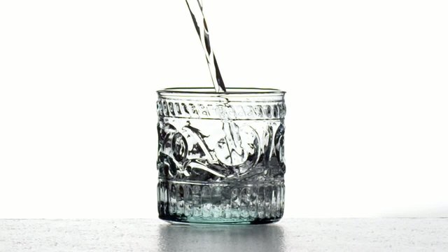 Eau remplissant un verre qui d&eacute;borde au ralenti