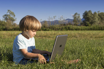 Young boy with notebook, sitting on the grass