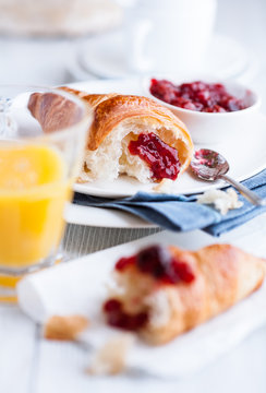 Croissant and sor cherry jam on a white plates