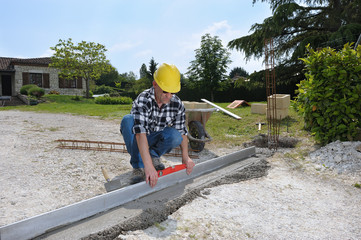 un ouvrier maçon qui nivelle du béton