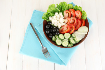 tasty Greek salad on white wooden background