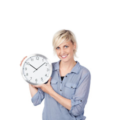 lachende blonde frau zeigt eine uhr