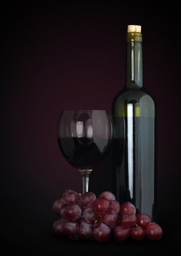red wine in glass with grapes and bottle