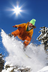 Snowboarder jumping against blue sky