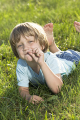 Fototapeta premium Young little boy lying on the grass