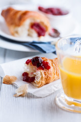 Croissant with sour cherry jam on kitchen table