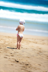 Fototapeta na wymiar little girl looking at sea while standing on the beach