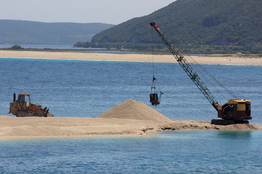dredger and bulldozer moving sand near the sea