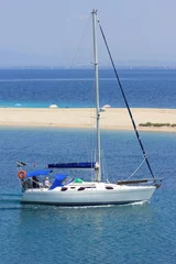 Fotobehang Sail yacht boat motoring by sea and sandy beach © William Richardson