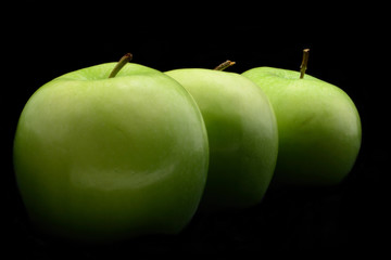 Three fresh green apples isolated over black