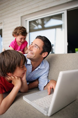 Father and children laughing at with a laptop