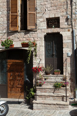 Fototapeta na wymiar Kwiaty w doniczkach na kamieniu kroki średniowieczny dom w Toskanii