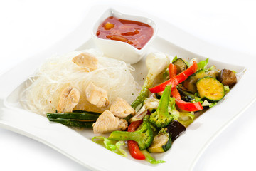 Roasted meat, rice noodles and vegetables on white background