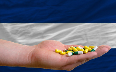 holding pills in hand in front of nicaragua national flag