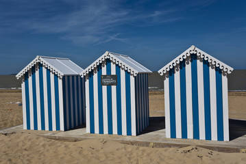 White and blue striped beach house on a sunny beach in France