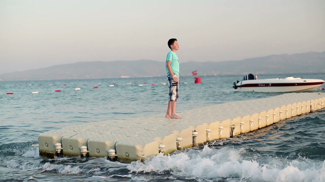 Young boy standing on platform floating on the water