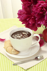 cup hot chocolate, apple, cookies and flowers on table in cafe