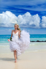 Fototapeta na wymiar Młoda kobieta w sukni panny młodej na brzegu morza