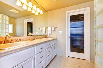 Large bathroom with white cabinets and glass shower.
