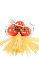 Glass bowl with spaghetti noodles, ripe tomatoes and garlic