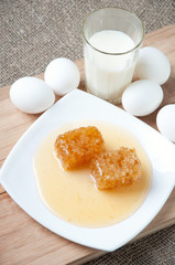 Glass plate with fresh honey, chicken eggs and milk