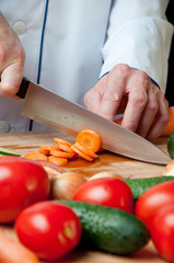 Close-up of chef's hands chopping fresh carrot