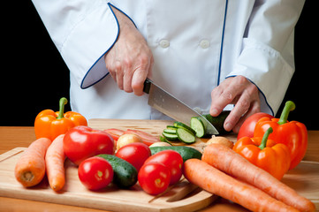 Chef cutting a fresh cucumber, studio shot