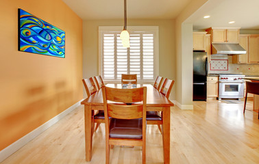 Orange dining room with hardwood floor and kitchen.