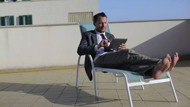 Happy businessman relaxing on sunbeds