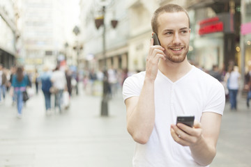 Men speaking on one mobile phone and holding secund cell in hand
