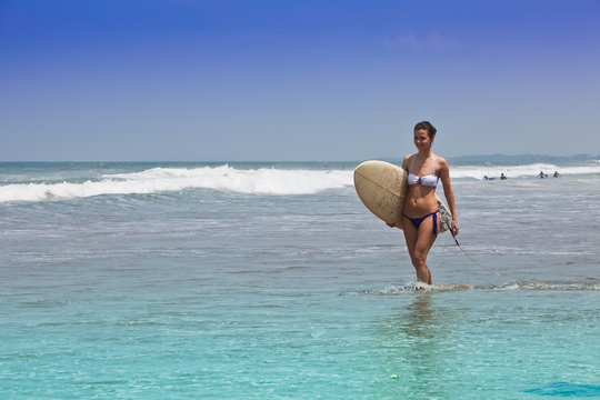 girl goes to bikini on an ocean coast with a board for surf