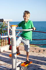 Little boy is engaged on exercise machines, in the open air