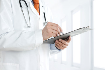 Doctor at the hospital writing notes on the clipboard
